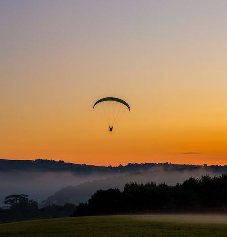 paramotor flying with sunset behind