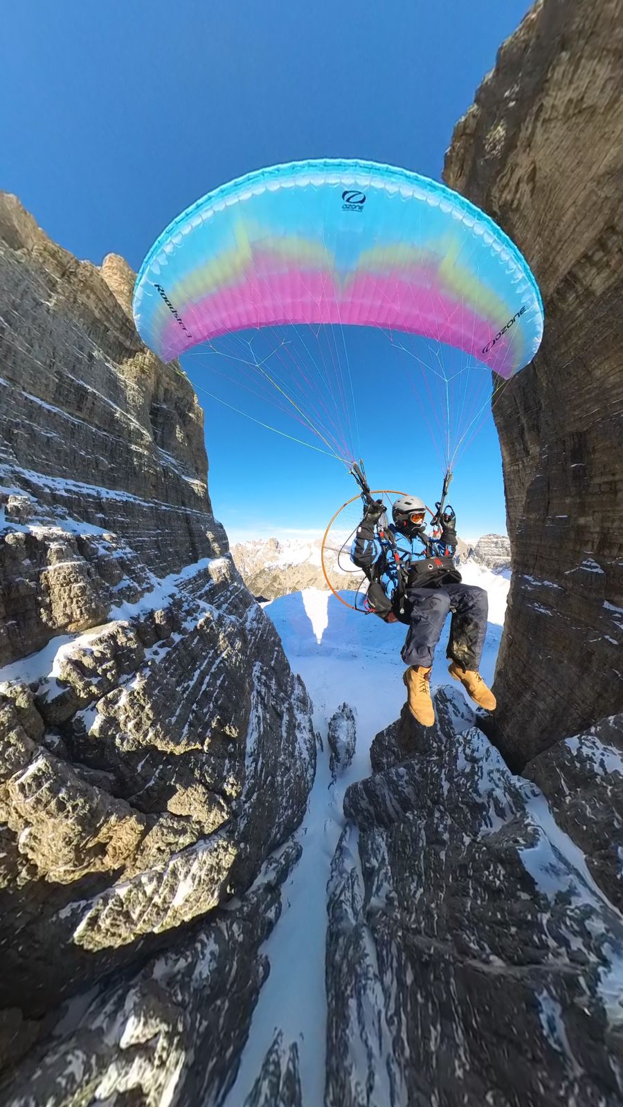 Man flying parajet through gap in mountains