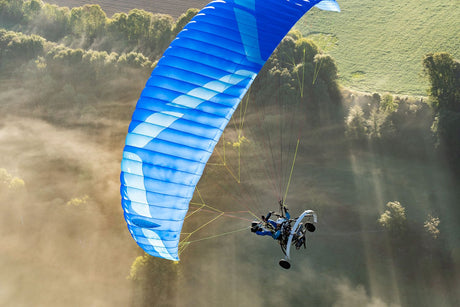 Flying paratrike with ground below