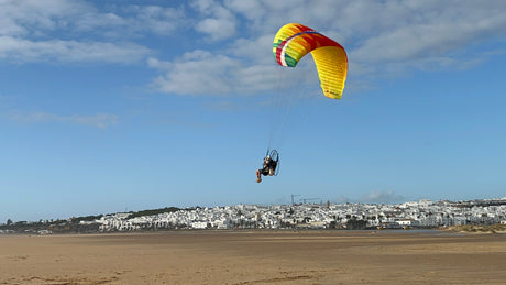 man landing a paramotor on a beach